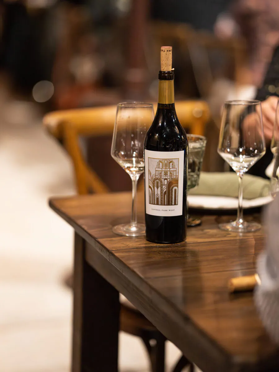 A bottle of red wine with a cork and two empty wine glasses are placed on a wooden table in a restaurant setting, evoking the charm of Napa Valley Events.